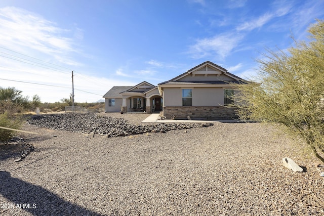 craftsman-style house with stone siding, a patio, and stucco siding