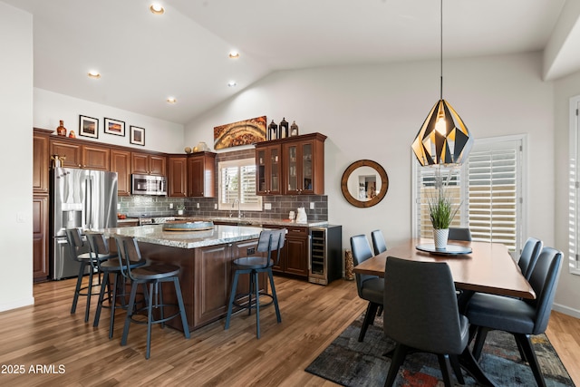 4029 N 160th Dr, Goodyear, AZ 85395 - kitchen with beverage cooler, appliances with stainless steel finishes, a breakfast bar, a kitchen island, and decorative backsplash