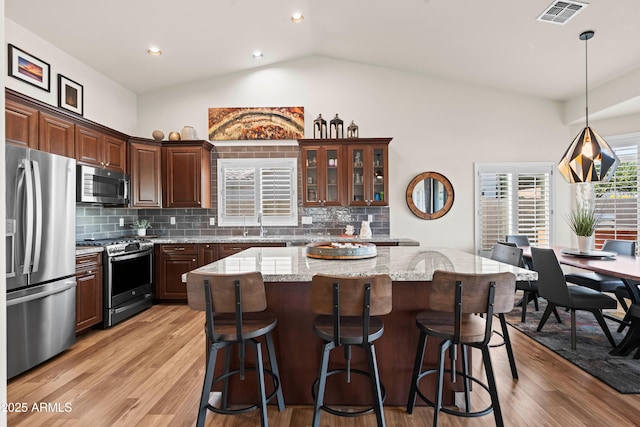4029 N 160th Dr, Goodyear, AZ 85395 - kitchen featuring appliances with stainless steel finishes, a kitchen bar, light wood-style floors, lofted ceiling, and recessed lighting