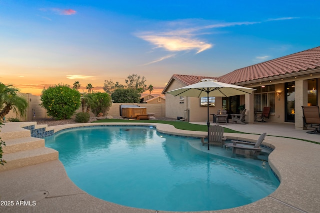 4029 N 160th Dr, Goodyear, AZ 85395 - pool at dusk with a hot tub, a patio, and a fenced backyard