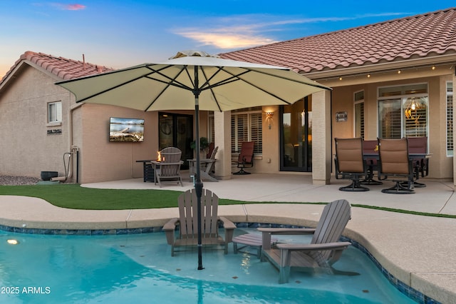 4029 N 160th Dr, Goodyear, AZ 85395 - back of house at dusk with a patio, stucco siding, a tiled roof, and a pool with connected hot tub