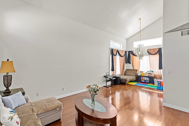 living room with hardwood / wood-style floors, a notable chandelier, and high vaulted ceiling