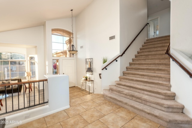 entrance foyer featuring a notable chandelier, light tile patterned flooring, and high vaulted ceiling