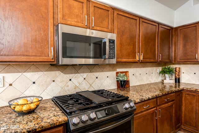 kitchen featuring stone countertops, backsplash, and range with gas stovetop