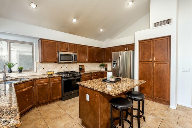 kitchen featuring stainless steel appliances, backsplash, a kitchen island, light stone counters, and sink