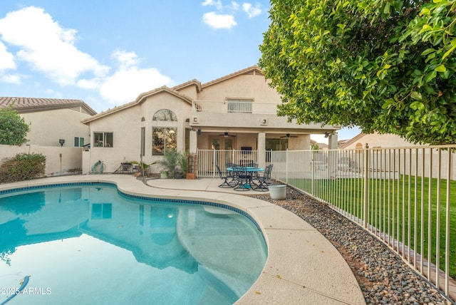 view of swimming pool with ceiling fan, a patio area, and a yard