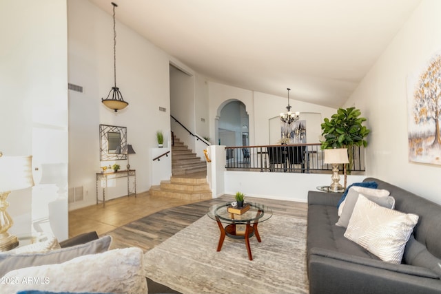 living room featuring lofted ceiling, tile patterned floors, and a chandelier