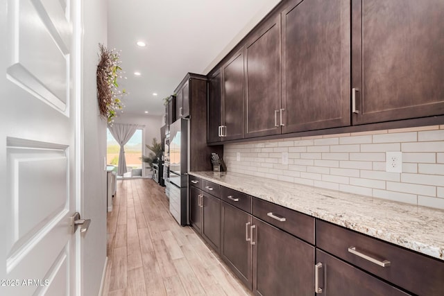kitchen featuring light wood-type flooring, decorative backsplash, and dark brown cabinets