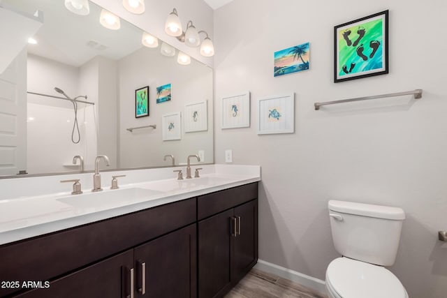 bathroom featuring a sink, toilet, double vanity, and walk in shower