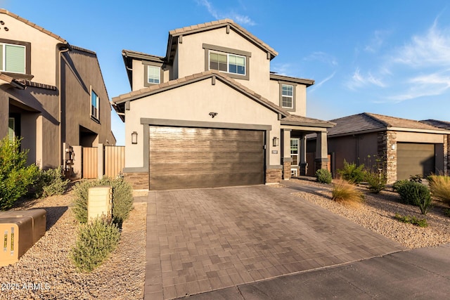 view of front of home featuring stucco siding, stone siding, decorative driveway, a tile roof, and a garage