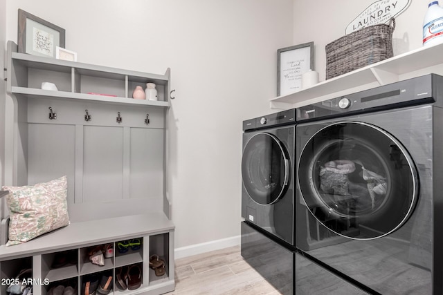 laundry area featuring independent washer and dryer, light wood finished floors, laundry area, and baseboards