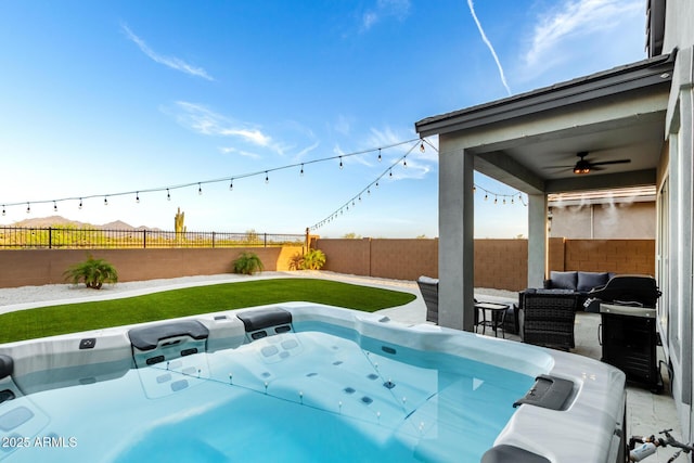 exterior space featuring a fenced backyard, a ceiling fan, a hot tub, and an outdoor hangout area