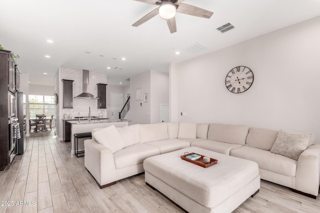 living area featuring light wood-style flooring, a ceiling fan, visible vents, and recessed lighting