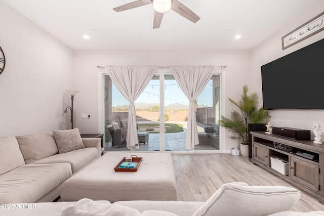 living area featuring light wood finished floors, a ceiling fan, and recessed lighting