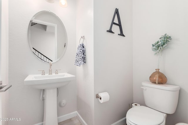 half bath with baseboards and toilet