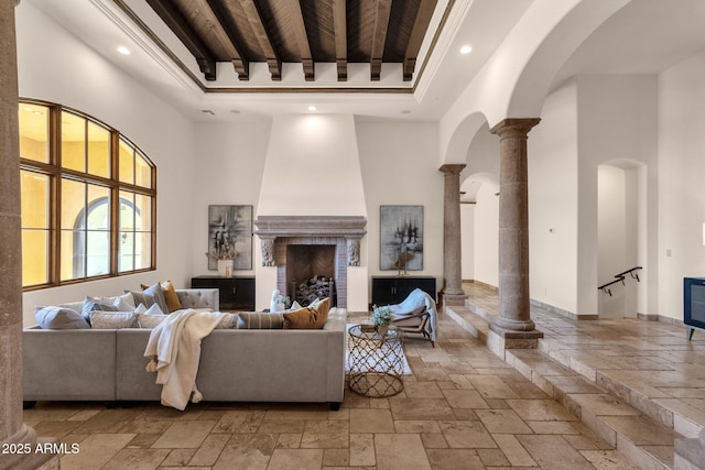 living area with beamed ceiling, a high ceiling, stone tile flooring, ornate columns, and recessed lighting