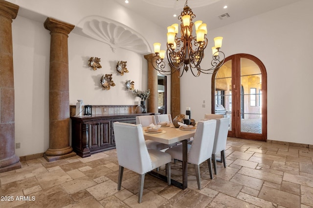 dining area with arched walkways, ornate columns, french doors, and stone tile floors