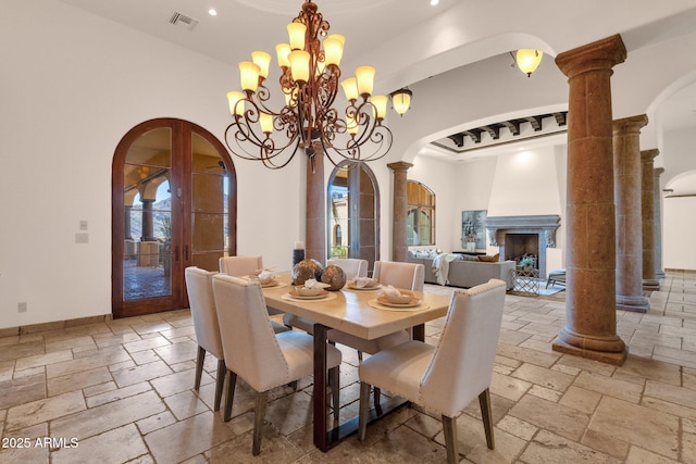 dining area featuring ornate columns, baseboards, arched walkways, and stone tile flooring