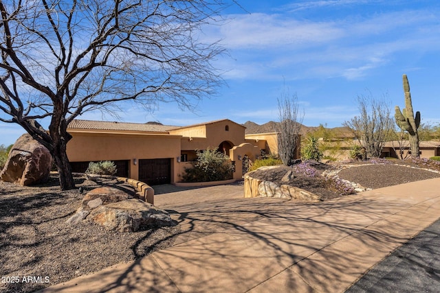 pueblo-style home featuring a garage, driveway, and stucco siding