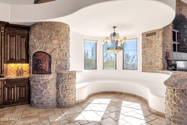 dining area featuring stone tile floors, visible vents, and a chandelier