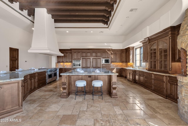 kitchen with stone tile floors, decorative backsplash, a kitchen breakfast bar, a center island, and built in appliances