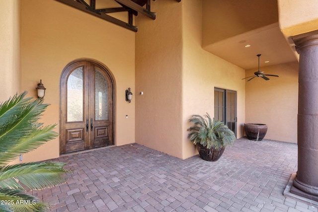 view of exterior entry with french doors, a patio area, a ceiling fan, and stucco siding