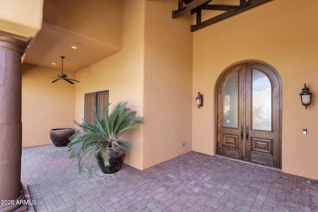 property entrance with a patio, french doors, a ceiling fan, and stucco siding