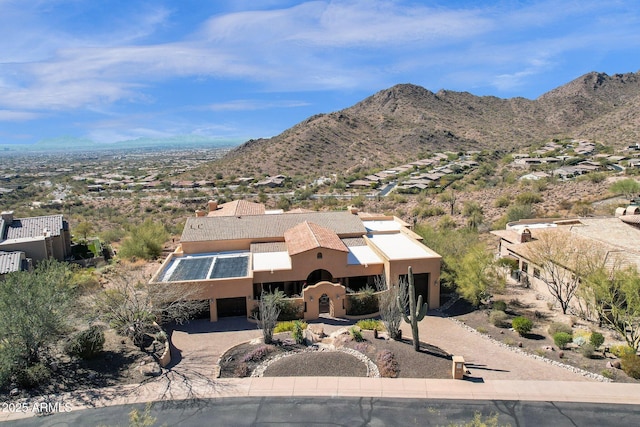 view of front of property featuring a garage, driveway, a mountain view, and stucco siding