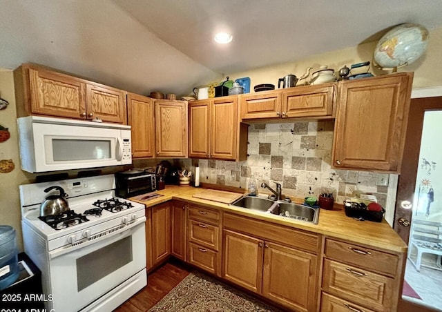 kitchen featuring dark wood-type flooring, lofted ceiling, sink, white appliances, and decorative backsplash