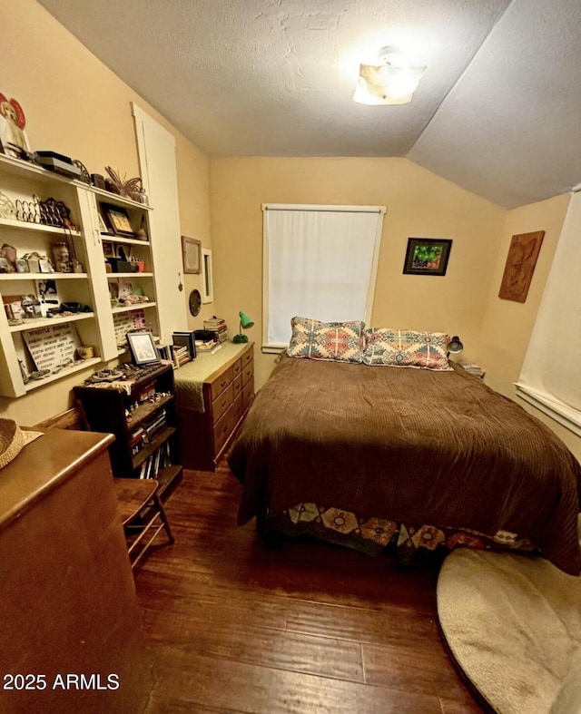 bedroom featuring dark wood-type flooring, lofted ceiling, and a textured ceiling