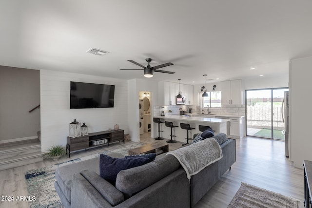 living room with stacked washing maching and dryer, ceiling fan, and light hardwood / wood-style floors