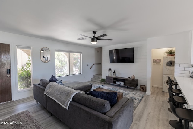 living room featuring stacked washer and clothes dryer, ceiling fan, and light hardwood / wood-style flooring