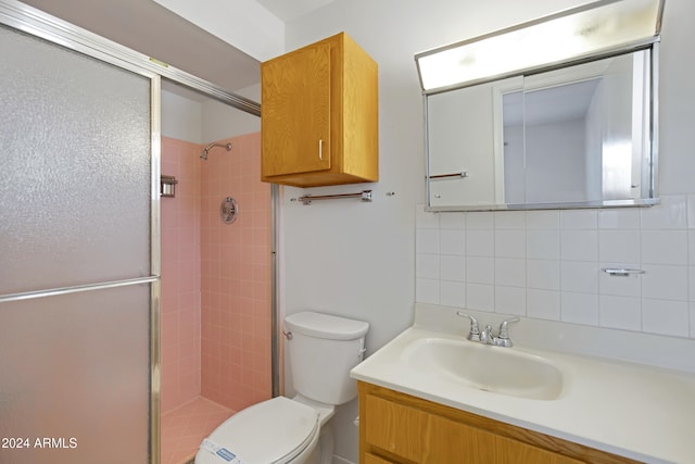 bathroom featuring vanity, toilet, walk in shower, and decorative backsplash