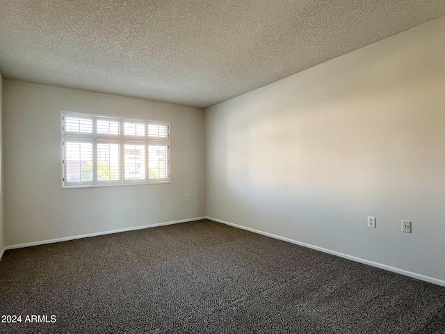 empty room with dark colored carpet and a textured ceiling