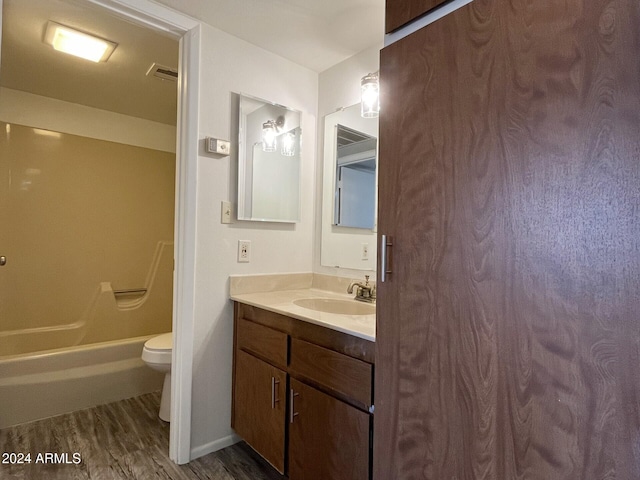 full bathroom with hardwood / wood-style floors, vanity, shower / bathtub combination, and toilet