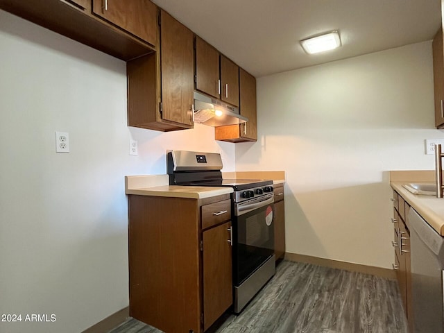 kitchen with dark hardwood / wood-style flooring, stainless steel stove, and sink