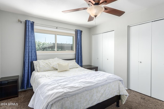 bedroom with multiple closets, dark carpet, and ceiling fan