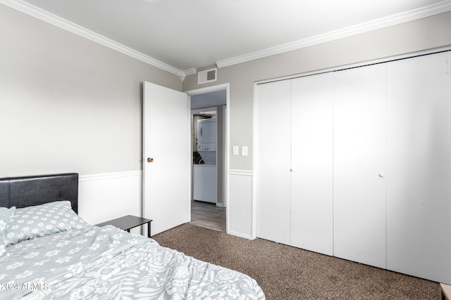 bedroom featuring stacked washer and dryer, dark colored carpet, a closet, and crown molding