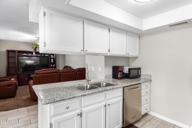 kitchen featuring light stone countertops, light carpet, white cabinets, sink, and dishwasher