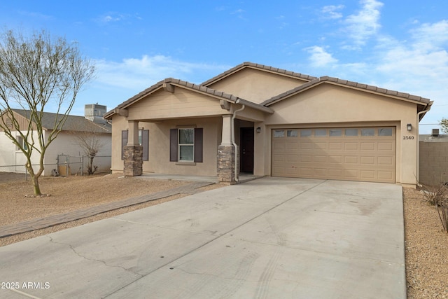 view of front of house featuring driveway, a tile roof, an attached garage, fence, and stucco siding