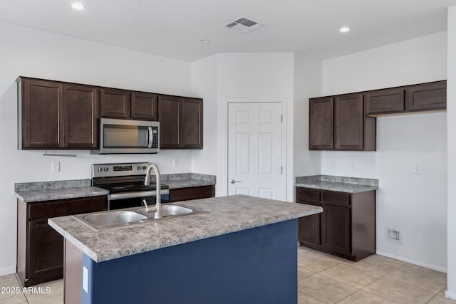 kitchen with dark brown cabinetry, visible vents, a center island with sink, and appliances with stainless steel finishes