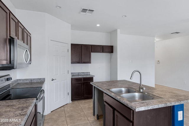 kitchen featuring a kitchen island with sink, dark brown cabinetry, a sink, visible vents, and appliances with stainless steel finishes