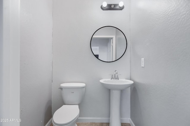 bathroom featuring a sink, toilet, and baseboards