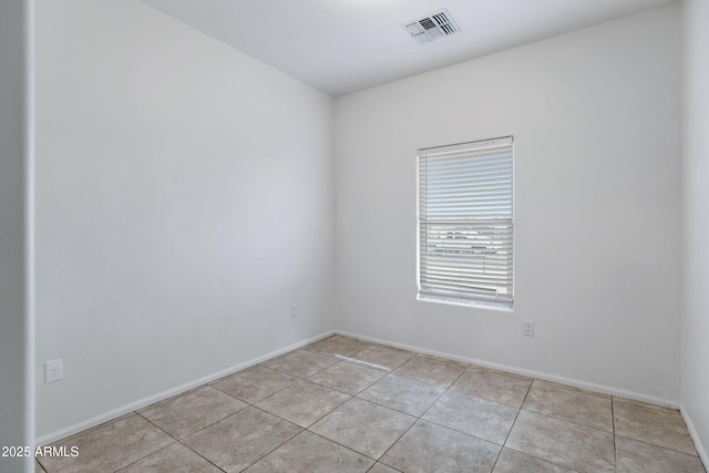 empty room with visible vents, baseboards, and light tile patterned floors