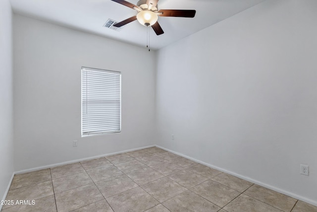 empty room with ceiling fan, light tile patterned flooring, visible vents, and baseboards