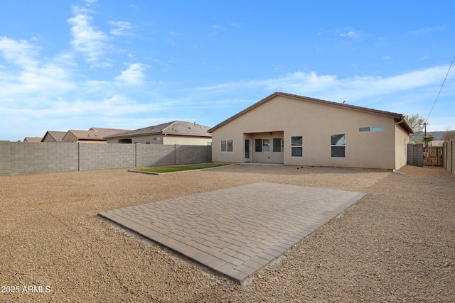 rear view of property featuring a fenced backyard, a patio, and stucco siding