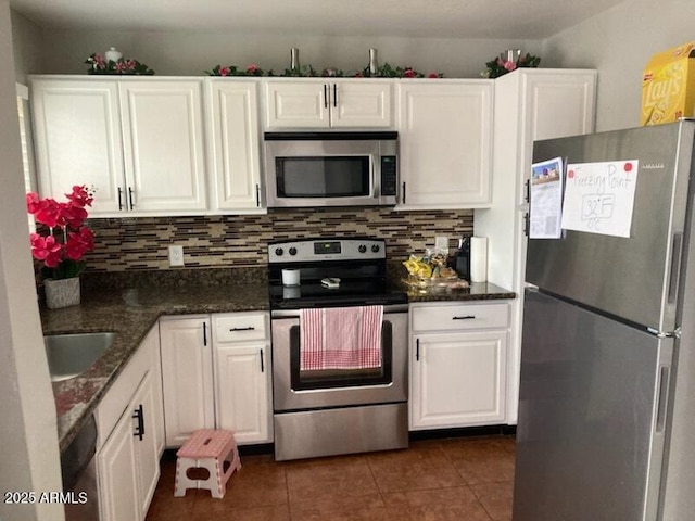 kitchen featuring white cabinetry, dark tile patterned flooring, decorative backsplash, and appliances with stainless steel finishes