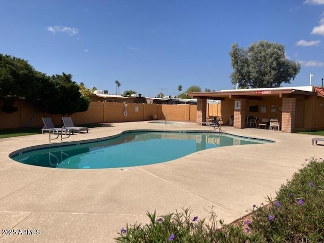 community pool featuring a fenced backyard and a patio
