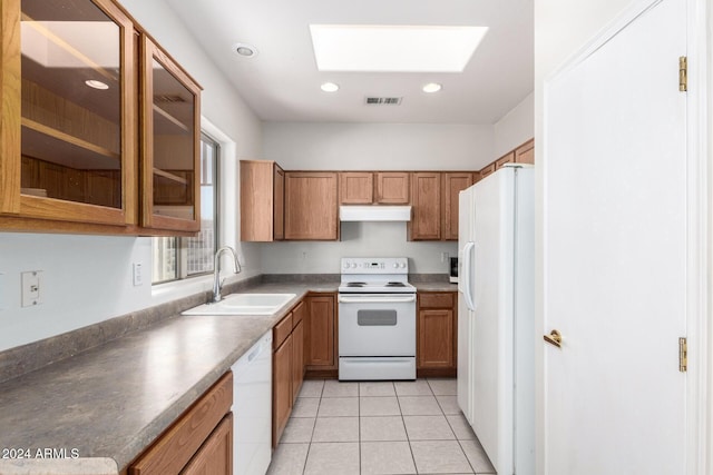 kitchen featuring a skylight, sink, light tile patterned floors, and white appliances