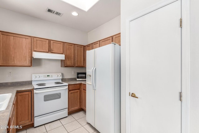 kitchen with light tile patterned flooring, white appliances, and sink